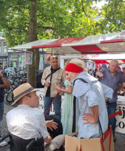 Mensen bij marktkraam op straat tijdens evenement.